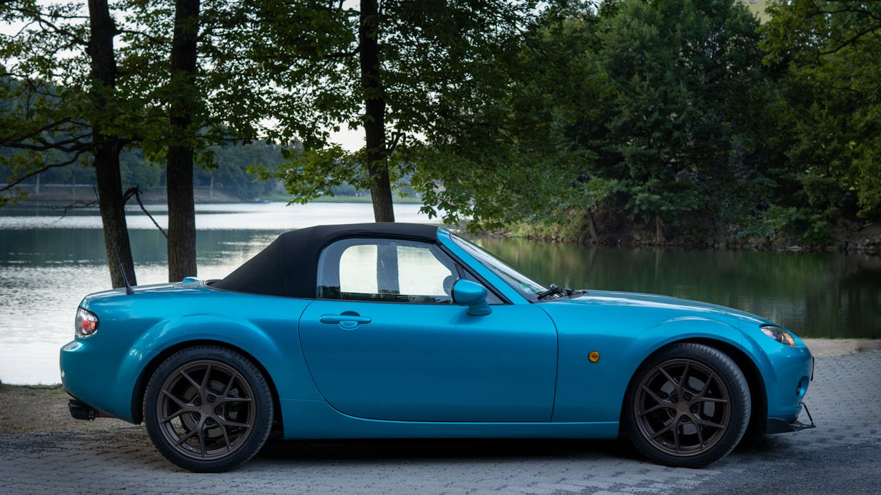 A vibrant blue Mazda MX5 parked by a serene lakeside in Počúvadlo, Slovakia.