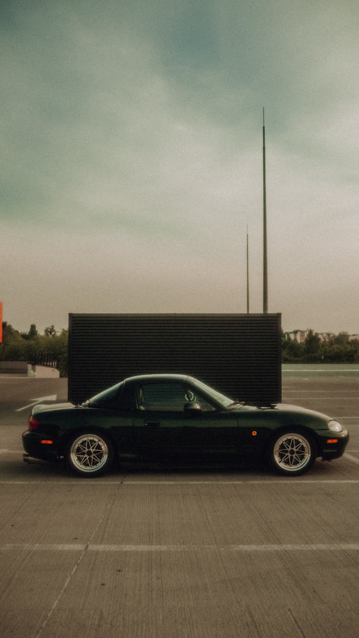 Side view of a black convertible sports car parked in a modern urban area.